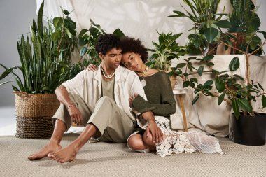 Genç çift, bereketli bitkilerle çevrili kapalı bir ortamda sevgi dolu bir şekilde kucaklaşır..