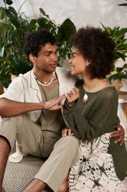 Canlı yeşil bitkiler ve hoş bir dekorla çevrelenmiş, birbirine eşlik eden sevgi dolu çift.