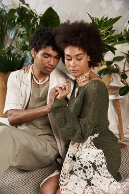 Bir çift, bitkilerle dolu şık bir iç mekanda rahatlarken sevgilerini sergiliyor..