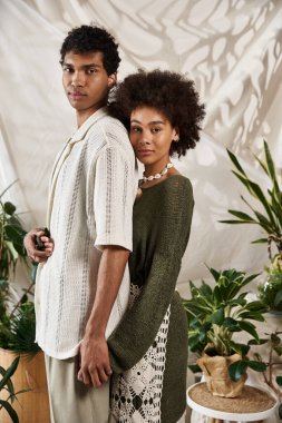 Genç bir çift, bereketli yeşilliklerle dolu şık bir mekanda birlikte durur, sevgi saçar..