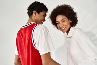 Genç bir çift, modaya uygun kıyafetler giyip, aşk ve mutluluk taşırken birbirlerine gülümsüyor..