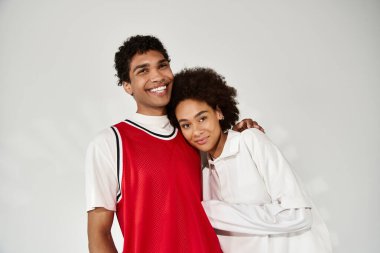 Sevgi dolu bir çift, şık bir stüdyoda birbirlerine gülümseyerek sarılır, sıcaklık ve bağ yayar..