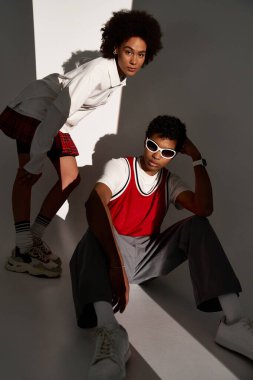 Bir çift tarzlarını benzersiz bir pozda sergiliyor, yumuşak ışık ve gölgelerle yıkanmış..