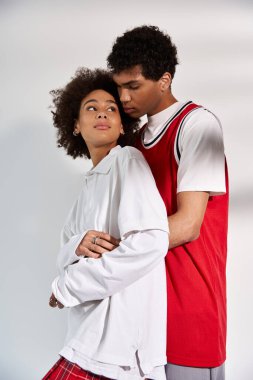 Genç bir çift, sevgi ve tarz yayarak, yumuşak ve minimal bir arkaplanda kucaklaşır..