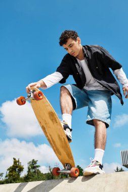 Genç bir adam ustaca parkta paten kayıyor. Gündüz vakti yeteneğini bir sörf tahtasında sergiliyor..