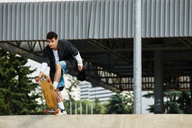 Genç bir adam enerjik bir parkta zahmetsizce paten kayarak atletizm ve neşesini sergiliyor..