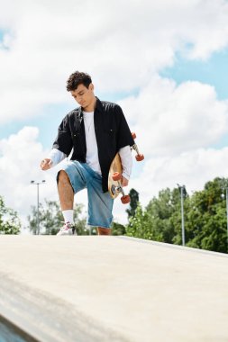 Genç bir adam parkta kaykaya biniyor, stil ve güvenle yeteneklerini sergiliyor..