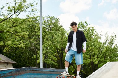 Genç bir adam, güneşli bir öğleden sonra kaykayıyla gezmeye hazırlanıyor..