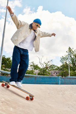 Genç bir adam kaykayını ustalıkla sürüyor, ağaçlarla çevrili pürüzsüz bir yüzeyde dengede duruyor..