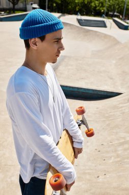 Canlı bir parkta, genç bir adam kaykayıyla dikiliyor, düşünceli bir şekilde uzaklığa bakıyor..