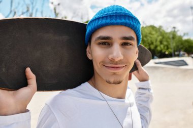 Parlak güneş ışığı, kaykayını tutarken neşeli bir gülümsemeyi aydınlatıyor..