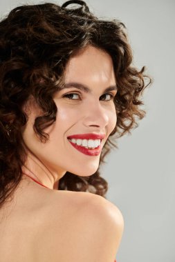 Parlak güneş kıvırcık saçlı, neşeli yaz tarzını sergileyen güzel genç bir kadını vurguluyor..