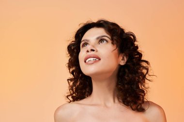 Güzel, genç bir kadın şık bir yaz elbisesi içinde neşeli bir ifadeyle yukarı bakıyor..