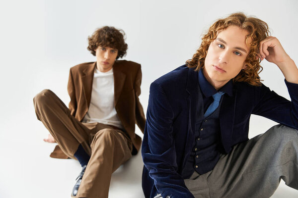 Два молодых человека демонстрируют свои модные наряды, творчески позируя в ярком пространстве..