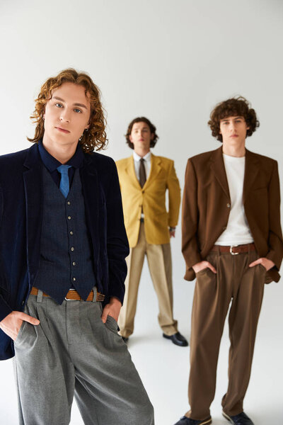 Трое молодых людей уверенно демонстрируют свои уникальные стили моды в модной обстановке.