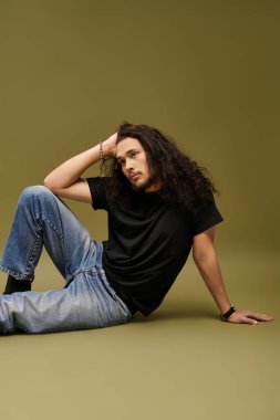 Sakallı yakışıklı genç bir adam minimalist yeşil bir arka plana yaslanıyor..