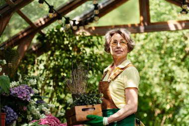 Huzurlu bir bahçede, zarif bir kadın sevgi dolu çiçekler ve bitkiler verir..