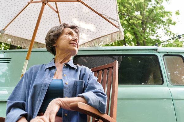 A radiant senior woman relaxes in a garden setting, appreciating the beauty around her.
