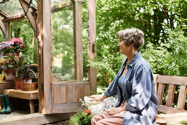 Senior woman sits calmly in a lush garden delighting in the beauty of nature and blooming flowers.