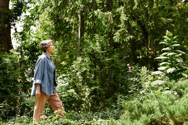 Graceful senior woman walks through a lush garden, embracing the beauty of nature and tranquility.