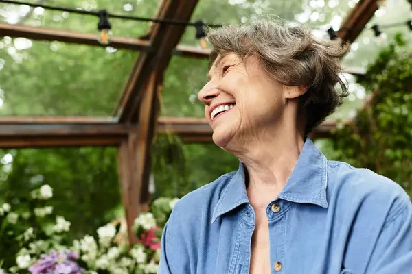 Yaşlı bir kadın bahçesinde huzurlu bir anın tadını çıkarıyor. Etrafı renkli çiçekler ve yeşilliklerle çevrili..