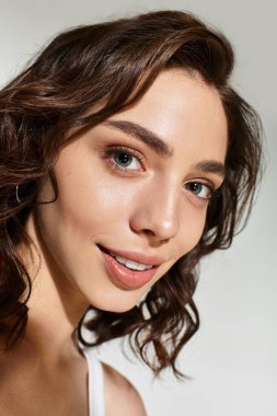 Büyüleyici makyajlı genç bir kadın stüdyo ortamında güven içinde poz veriyor..