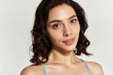 Büyüleyici genç bir kadın stüdyoda zarifçe poz veriyor, makyajı doğal güzelliğini arttırıyor..