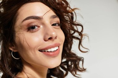 Genç bir kadın güzel makyajını sergileyerek kendine güvenerek stüdyoda poz veriyor..