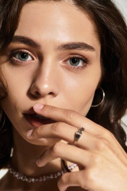Büyüleyici makyajlı genç bir kadın şık bir stüdyo ortamında zarifçe poz veriyor..