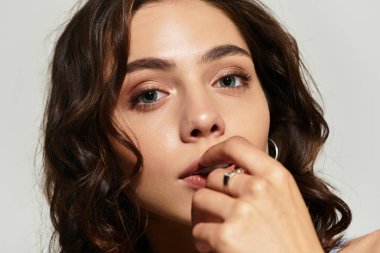 Güzel genç bir kadın zarif bir pozla stüdyo ortamında çarpıcı bir makyajla poz veriyor..