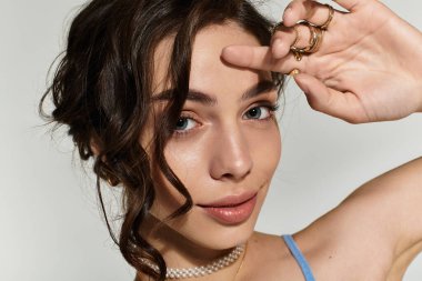 Çekici genç bir kadın zarif bir şekilde poz verir, modern bir stüdyoda güzel makyajını gösterir..