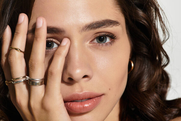 A young woman poses gracefully in a studio, showcasing her elegant makeup and beauty.