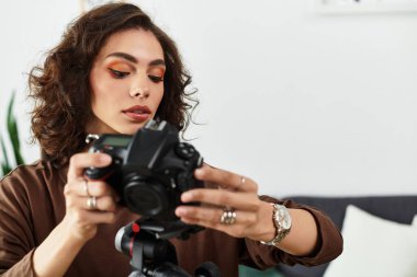 Kıvırcık saçlı genç bir kadın rahat bir ofis ortamında kamerasına odaklanıyor..