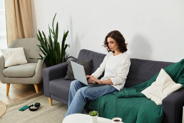 Kıvırcık saçlı serbest çalışan evde rahat çalışıyor, sakin bir atmosferin tadını çıkarıyor..