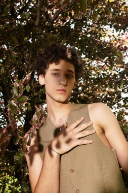 Şık genç adam, doğanın güzellikleriyle çevrili canlı bir parkta güneşli bir günün tadını çıkarıyor..