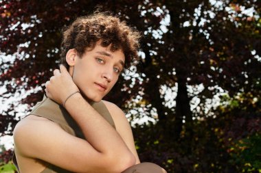 Şık bir genç adam, canlı bir parkta güneşli bir günün tadını çıkarıyor..