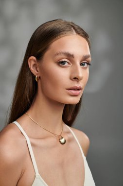 Genç bir kadın doğal güzelliğini bronz teniyle ve açık renk makyajıyla bir stüdyoda sergiliyor..