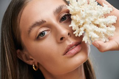 Genç bir kadın yaz stüdyosunda doğal makyajını ve mercanını sergiliyor..