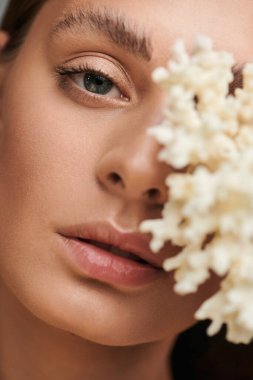 Güneş yanığı tenli genç bir kadın stüdyo ortamında mercanlarla doğal güzelliğini sergiliyor..