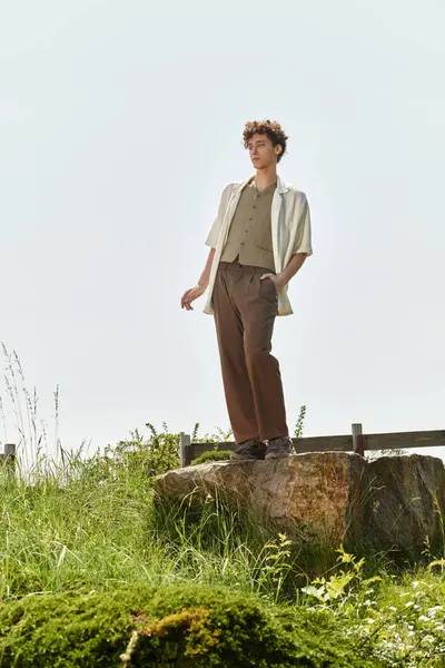 Kıvırcık saçlı şık bir genç adam güneşli bir günde yemyeşil bir parkta rahatlar..