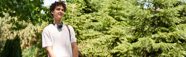 A young man with curly hair relaxes in a vibrant summer park, embracing nature and tranquility, banner