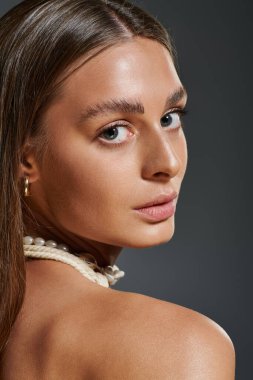 Bronz tenli genç bir kadın deniz kabuğundan bir kolye ile süslenmiştir..