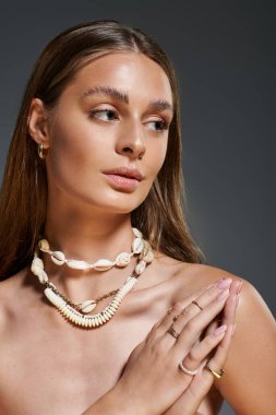 Bronz tenli genç bir kadın yaz deniz kabuğu kolyesinde zarifçe poz verir..