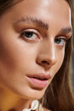 Güzel genç bir kadın canlı bir stüdyoda yaz elbisesini ve deniz kabuğu kolyesini sergiliyor..