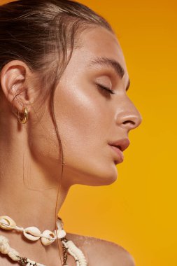 Güneşli kıyafetli genç bir kadın, bronz teniyle ve deniz kabuğundan kolyesiyle gösteriş yapıyor..