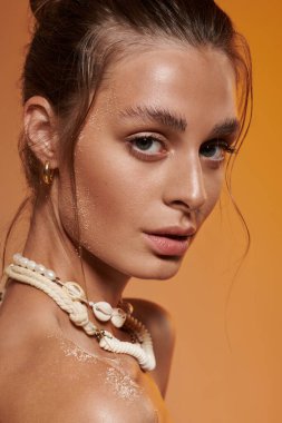 Genç bir kadın, kendine güvenen bir şekilde poz verirken ışıl ışıl güzelliğini bir yaz elbisesiyle sergiliyor..