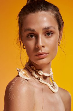 Çekici genç bir kadın canlı bir stüdyoda deniz kabuğu kolyesiyle yaz modelliği yapıyor..