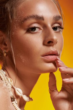 Bronz tenli genç bir kadın zarif poz veriyor. Yazlık elbisesini ve deniz kabuğu kolyesini gösteriyor..