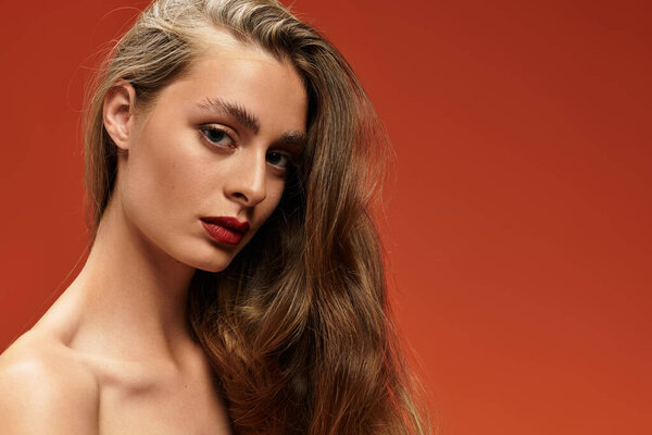 Портрет молодой красивой женщины с развевающимися волосами и смелым макияжем, подчеркивающим ее черты.