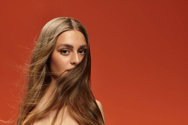 Genç ve güzel bir kadın, saçları zarif bir şekilde gözlerinin önünde dalgalanırken kendine güveniyor..